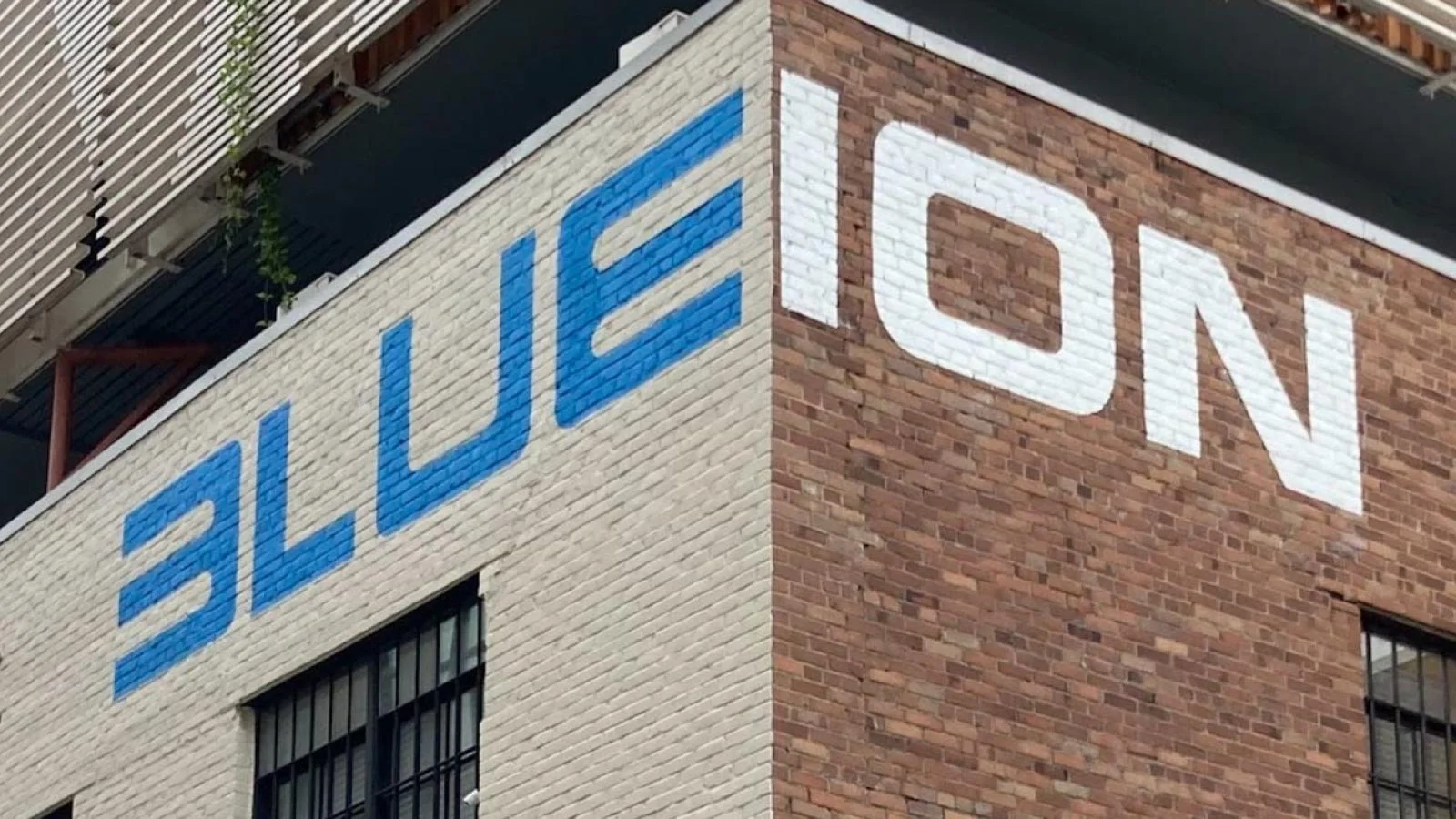 Large corporate signage for Blue Ion painted across the corner of a multi-colored brick building.